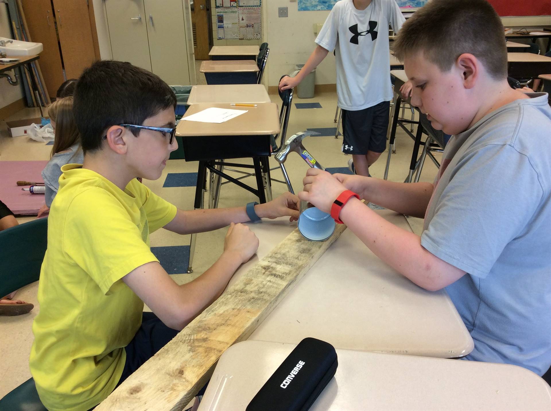 two boys working together to attach items to a board