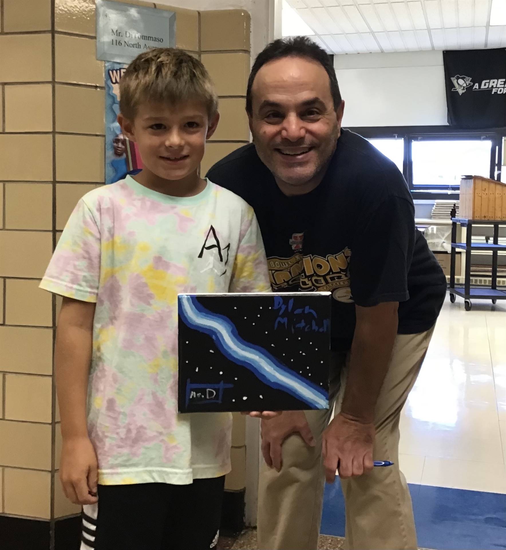 A teacher and boy holding a painting 