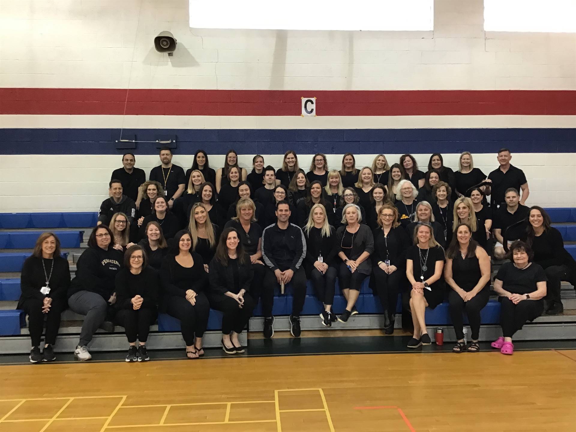 SAES staff posing in bleachers in gym